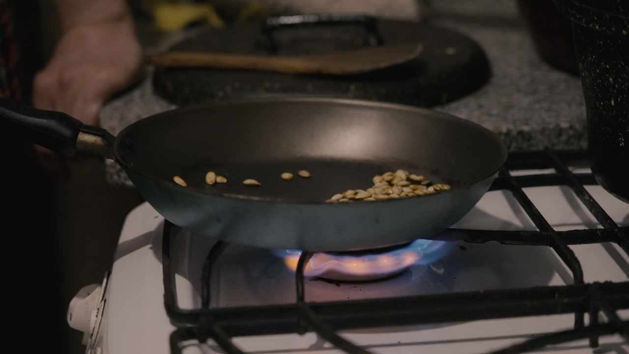 Rister græskarkerner på en stegepande på et gaskomfur