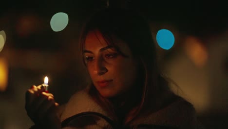 young dressed girl with coat and open hair, lighting and staring at the yellow flame of lighter in dark with neon light