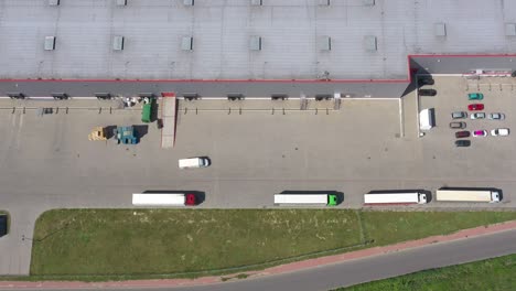 Moving-Aerial-Side-Shot-of-Industrial-Warehouse-Loading-Dock-where-Many-Truck-with-Semi-Trailers-Load--Unload-Merchandise