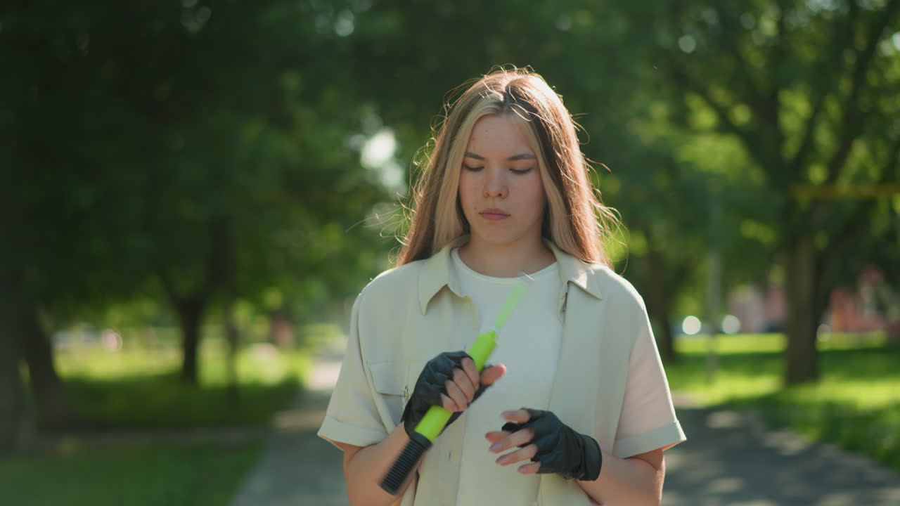 야외에서 산책하는 젊은 여성, 빛에서 녹색 공기 프를 검사, 그녀의 사려 깊은 표정을 강조 반사, 배경에는 울창한 나무와 초록색을 포함합니다