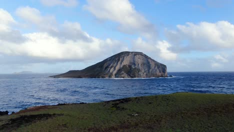 drone flying back away from mini island above another hawaiian island