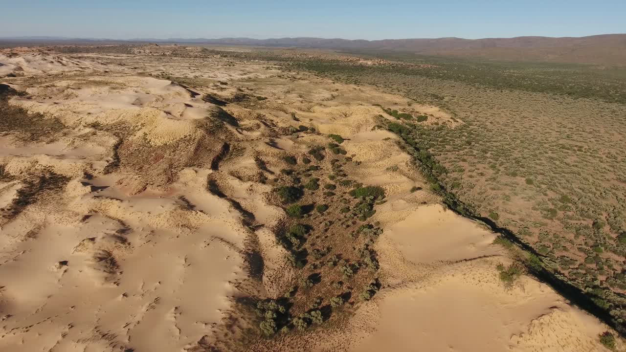vista aérea de dunas de arena masivas entre montañas rocosas en la región árida del cabo norte, sudáfrica