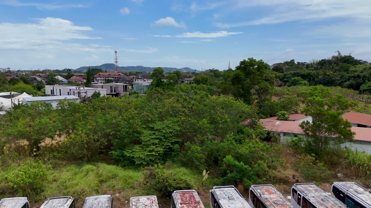 드론 영상은 태국 푸켓에 있는 버스 정류장을 포착하고 있습니다. 은 하늘 아래 녹색으로 뒤인 차량과 녹색이 얼어붙은 모습입니다.
