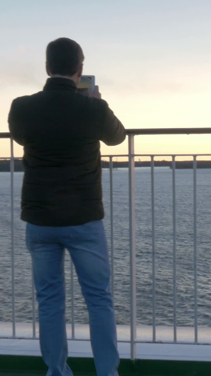 Man Taking Picture on Ferry at Sunset