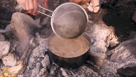 brewing chai tea over a small campfire in pulau ubin, singapore - close up