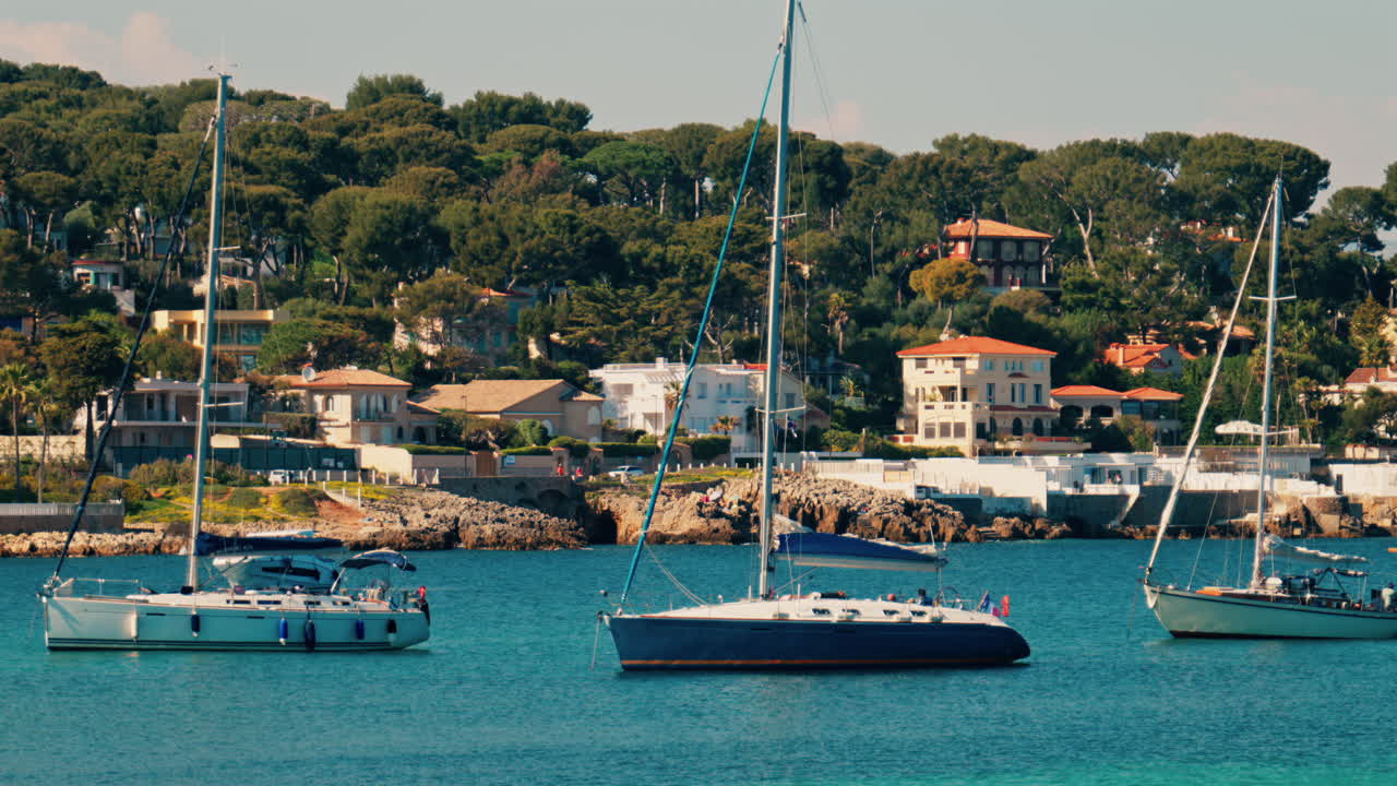Boats docked on the sea with villas surrounded by greenery in the background