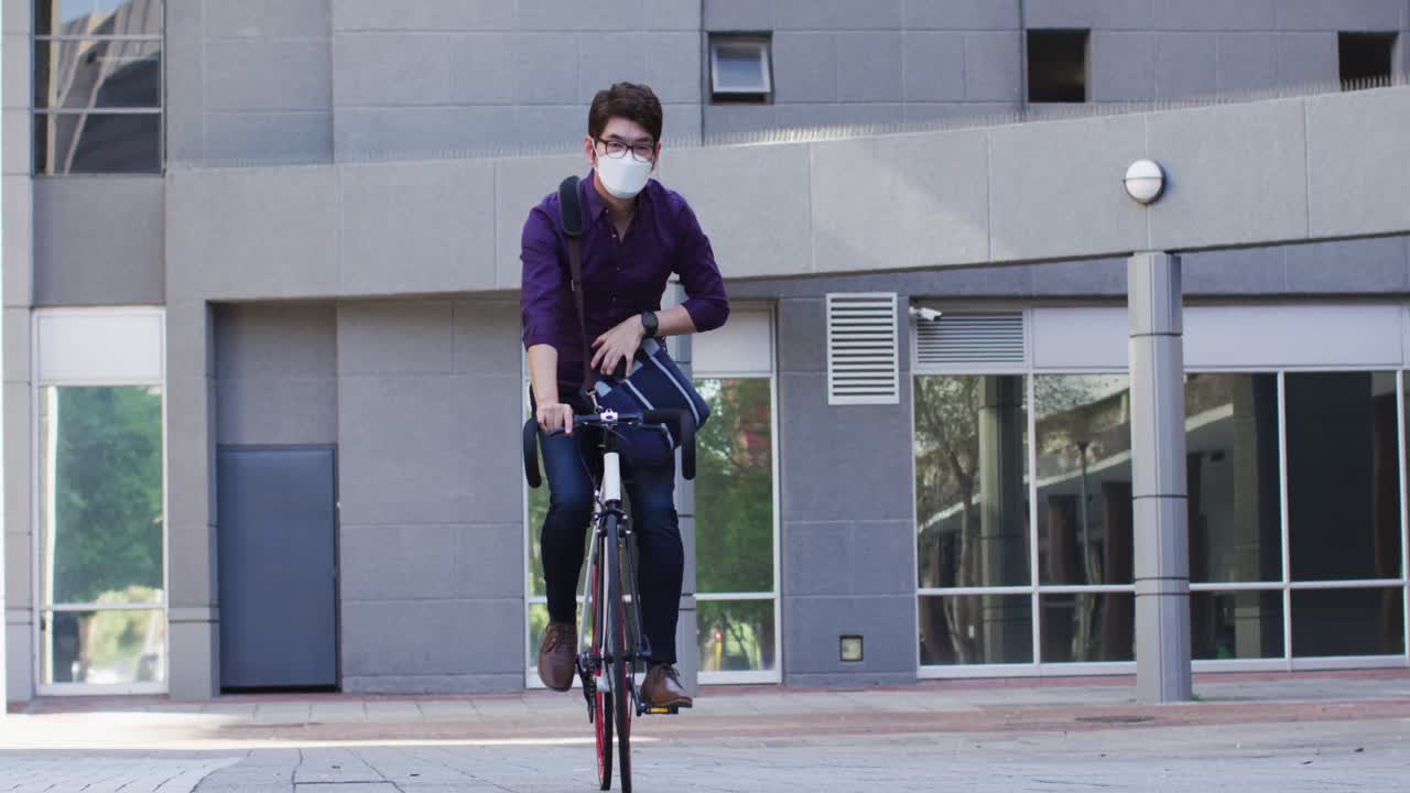 얼굴 마스크를 쓴 아시아 남자가 회사 공원에서 자전거를 타고