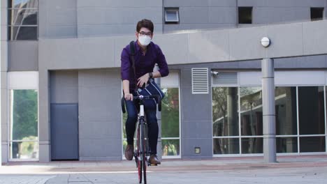 hombre asiático con máscara facial montando en bicicleta en el parque corporativo