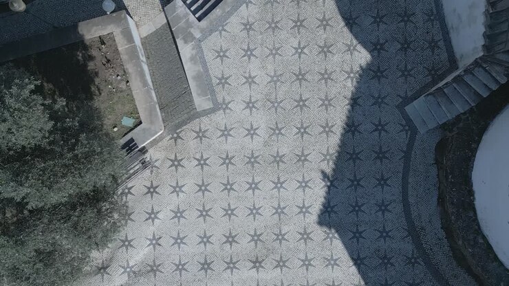 Top down aerial backwards panning view of famous chapel of Santo Amaro sidewalk with some trees shadows in Lisbon, Portugal
