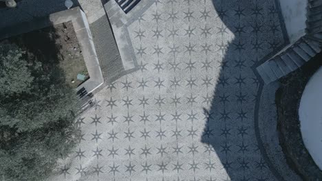 top down aerial backwards panning view of famous chapel of santo amaro sidewalk with some trees shadows in lisbon, portugal