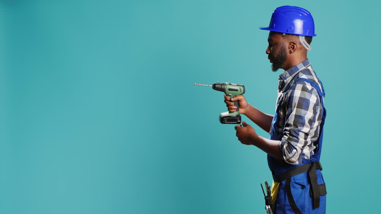 Male builder using power drill instrument on wall