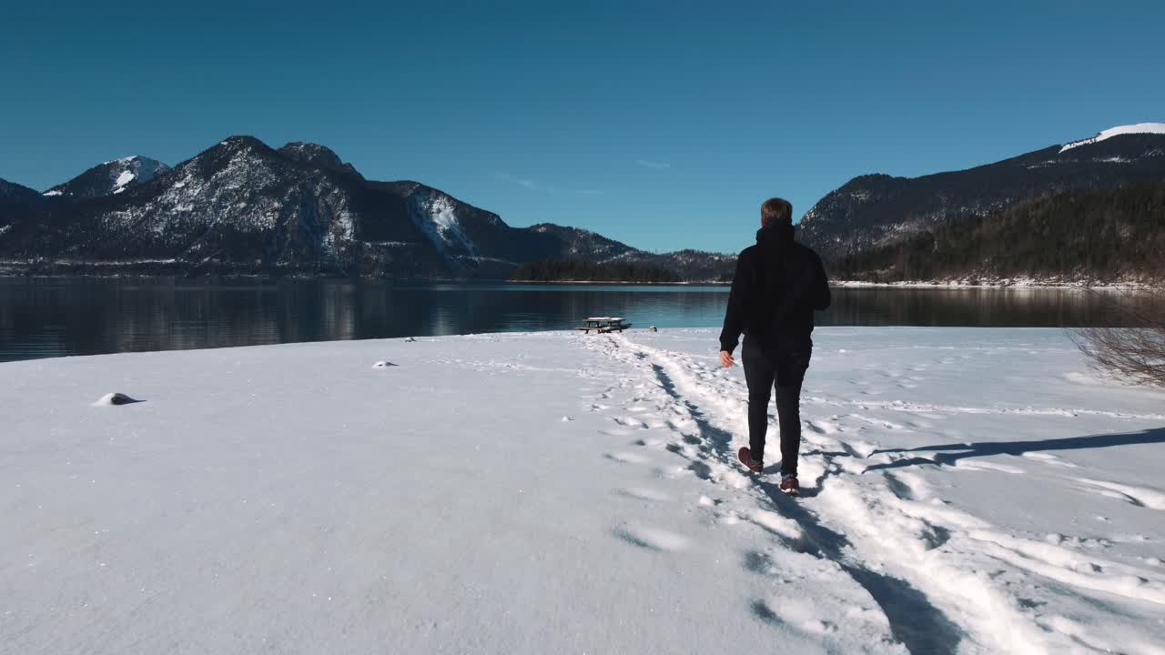 joven en una playa cubierta de nieve en el lago walchensee en baviera, alemania del sur en las montañas de los alpes cerca de austria