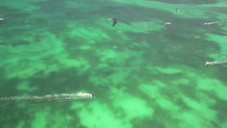 kitesurfers glide over turquoise waters near a yacht in crasky