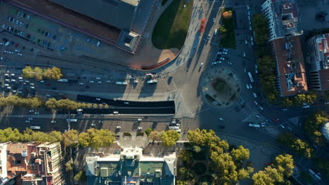 Aerial-birds-eye-overhead-top-down-ascending-shot-of-traffic-on-roundabout-and-surrounding-multilane-roads-in-city.