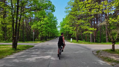 Slow-motion-shot-of-a-man-on-bicycle-in-the-park-surrounded-by-trees-on-a-sunny-day