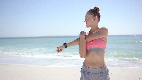 Joven-Caucásica-Estirando-Su-Brazo-En-Una-Playa-Soleada,-Con-Espacio-Para-Copiar