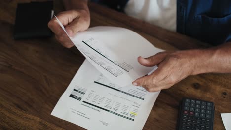 unrecognizable man browsing high paper bills for energy.