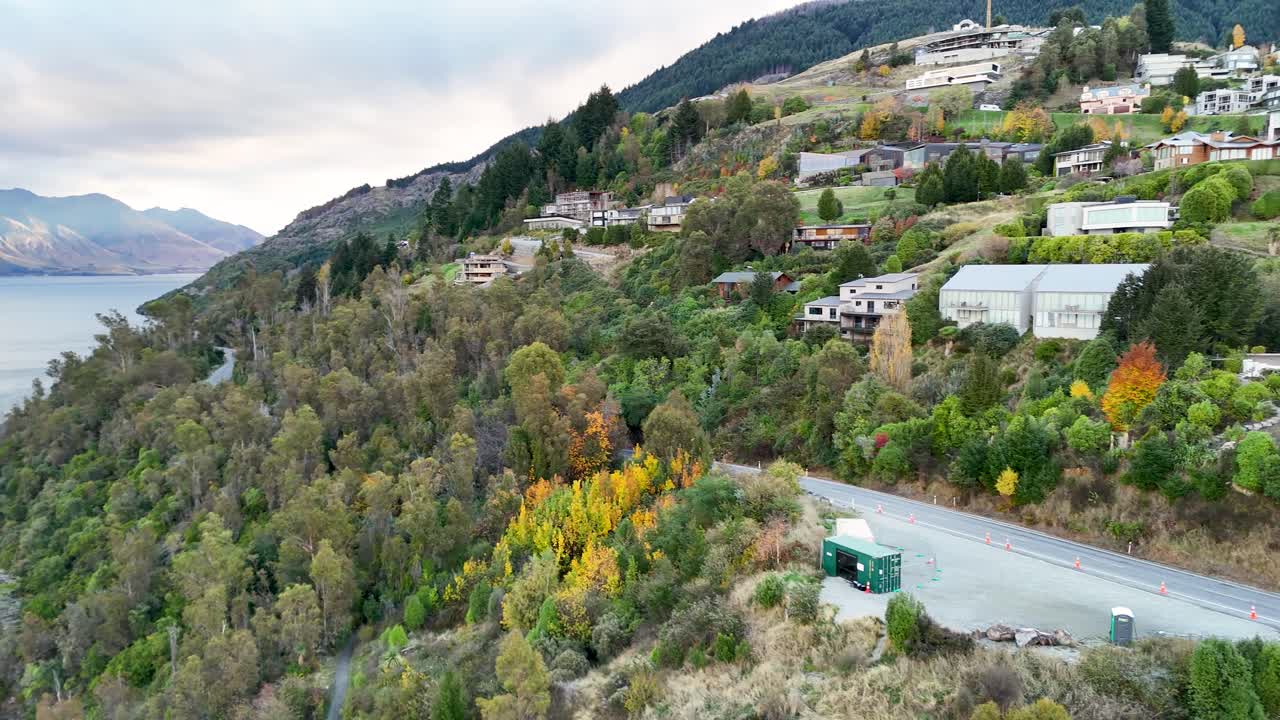 Aerial footage captures Queenstown's lush hills and Lake Wakatipu under soft daylight, showcasing vibrant autumn foliage and serene landscapes