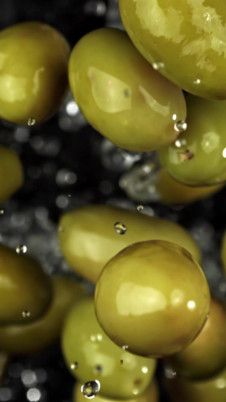 Olive verdi fresche che cadono con gocce d'acqua in super rallentatore