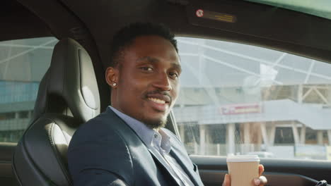 man drinking coffee in electric car