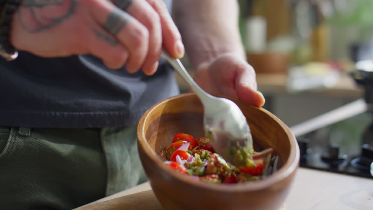 Hands of Chef Mixing Salad with Pesto Dressing