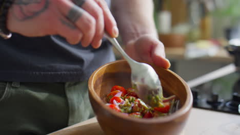 hands of chef mixing salad with pesto dressing