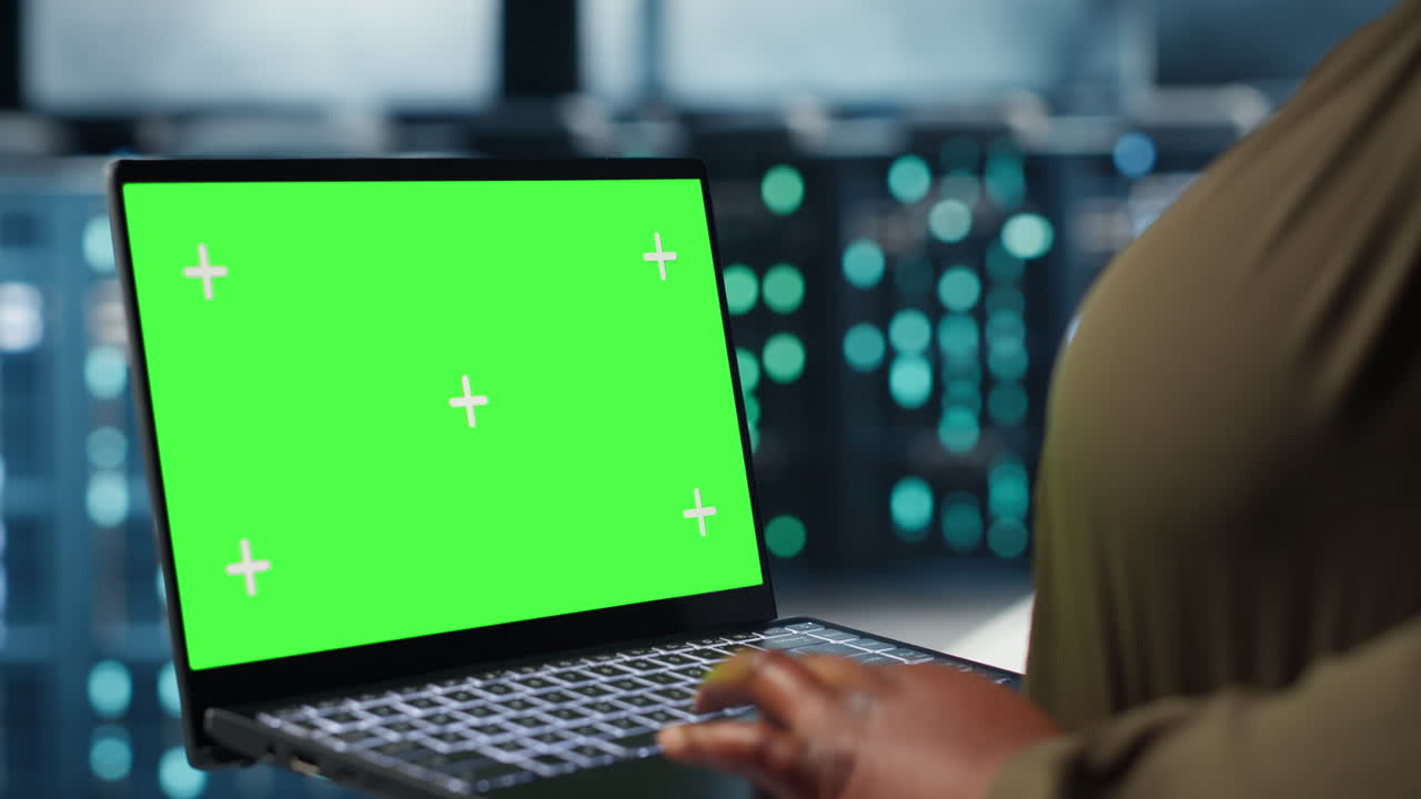 Primo piano di un admin che lavora in un data center utilizzando un portatile con green screen