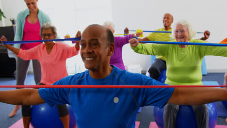 Front-view-of-Caucasian-female-trainer-training-senior-people-in-exercise-at-fitness-studio-4k