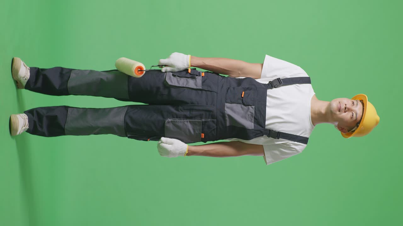 Full Body Of Asian Man Painter Wearing Safety Helmet Standing And Look Around In The Green Screen Background Studio