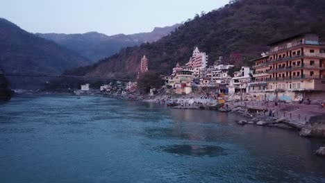 Lakshman-Jhula-Brücke-Unter-Ruhigem-Wasser-Mit-Tera-Manzil-Tempel-Im-Fluss-Ganges,-Uttarakhand,-Indien