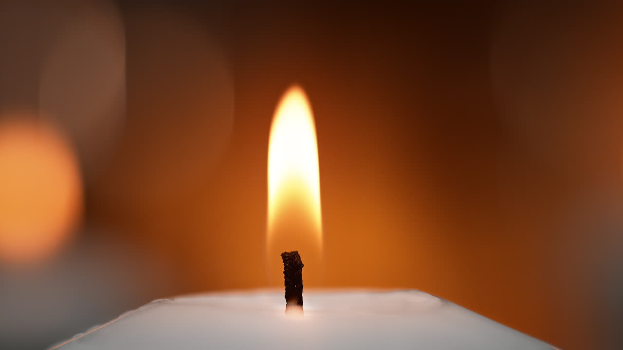 fiocco di candela e fiamma in macro su uno sfondo arancione caldo in uno spazio di meditazione e rilassamento