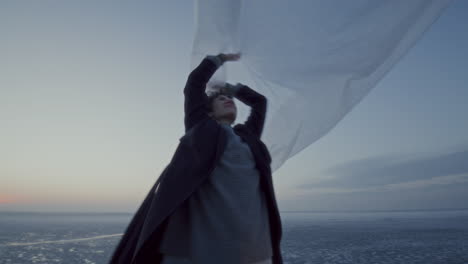 couple playing with flowing fabric in breeze near frozen lake at sunset