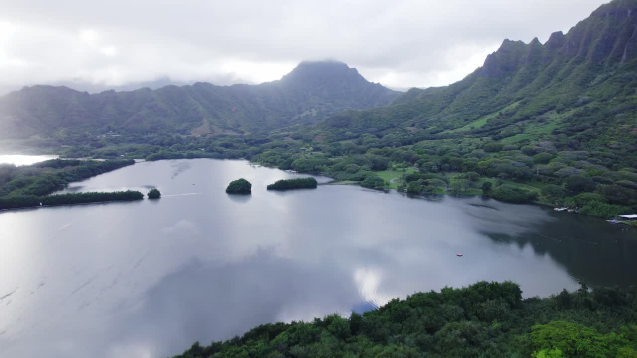 una fascinante vista aérea de un lago tranquilo rodeado de exuberante vegetación y altas montañas, con una atmósfera brumosa que crea un ambiente místico