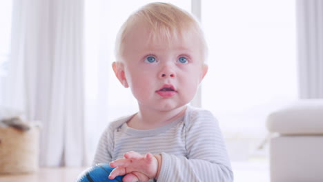 niño pequeño blanco sentado en el suelo sosteniendo la pelota, de cerca