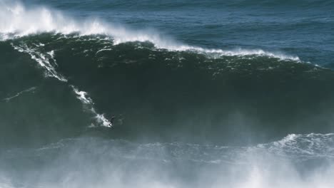 slow motion of a big wave surfer riding one of the biggest monster waves in nazaré, portugal