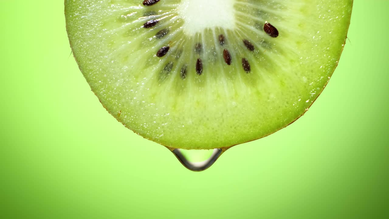 perto ou macro de uma fatia de kiwi, uma gota de água cai em câmera lenta.