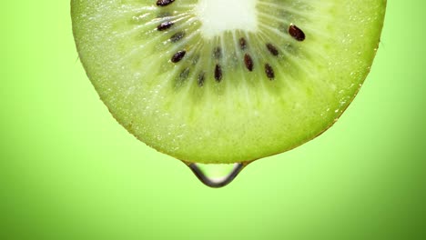 close up or macro of a slice of kiwi, a drop of water falls in slow motion.