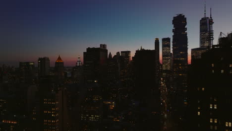 Aufsteigende-Luftaufnahmen-Der-Stadt-In-Der-Abenddämmerung.-Silhouetten-Von-Wolkenkratzern-In-Der-Innenstadt-Vor-Farbenfrohem-Dämmerungshimmel.-Manhattan,-New-York-City,-Vereinigte-Staaten