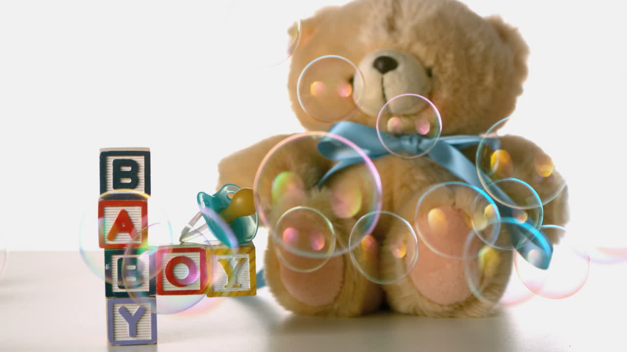 Bubbles floating over baby blocks soother and teddy bear