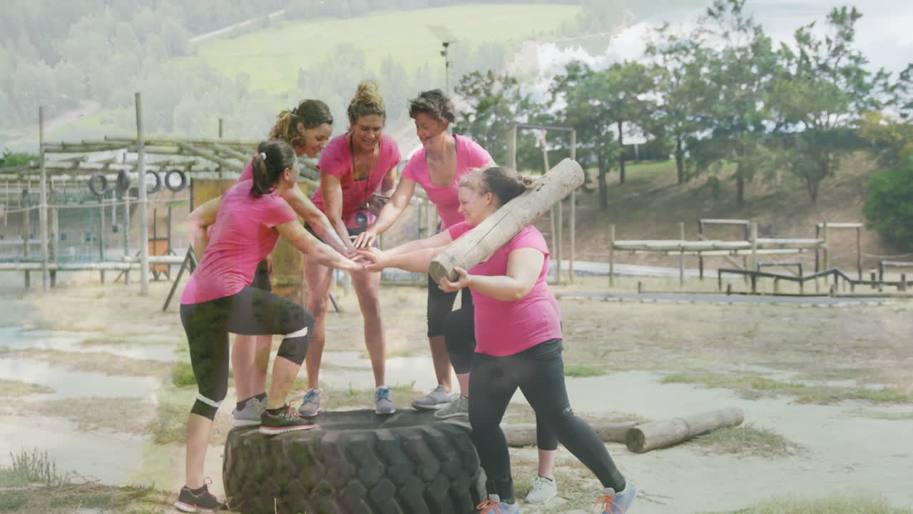 Cheering in pink shirts, women participating in outdoor team-building exercise