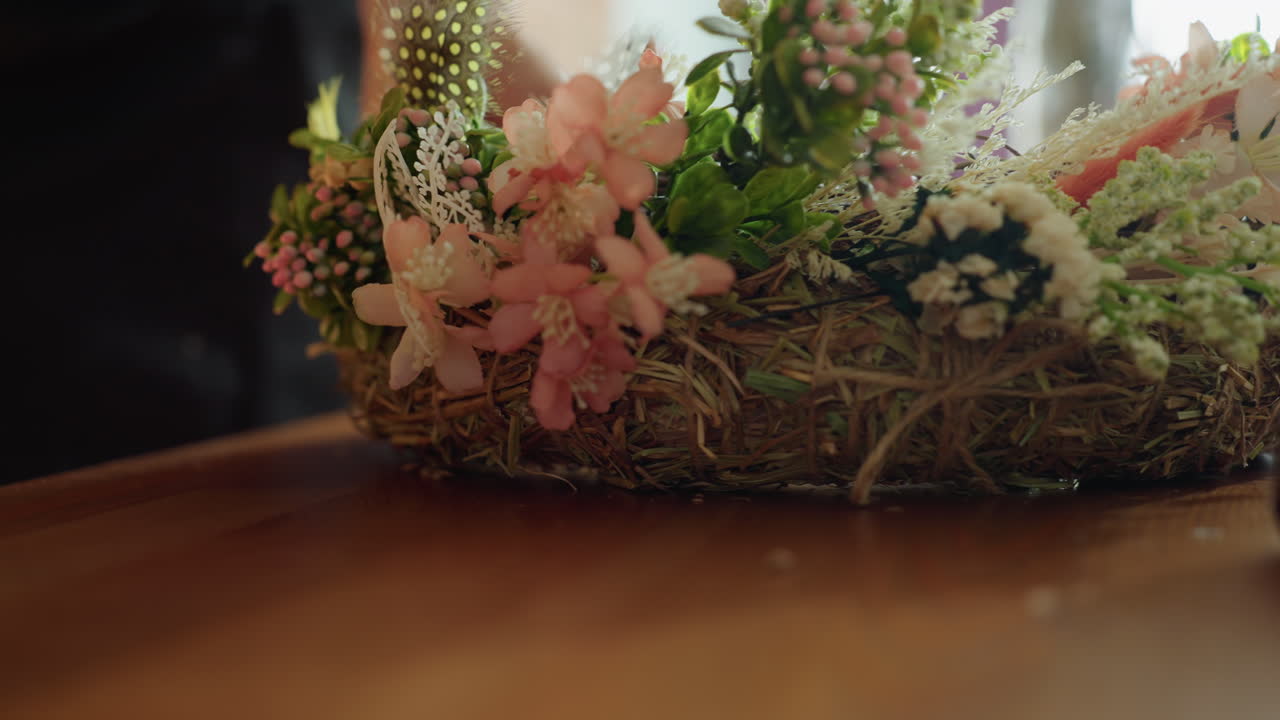Tangan menata karangan bunga rustic dengan bunga, tanaman hijau, dan ranting di atas meja kayu, perangkai bunga pengrajin bekerja dengan bahan-bahan alami untuk menciptakan desain floral buatan tangan dekoratif di ruang kerja kreatif yang cerah dan nyaman