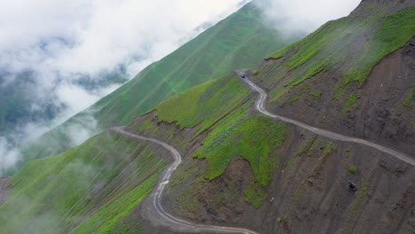 wide cinematic drone shot of vehicle driving on one of the world's most dangerous roads, the of the abano pass in tusheti georgia