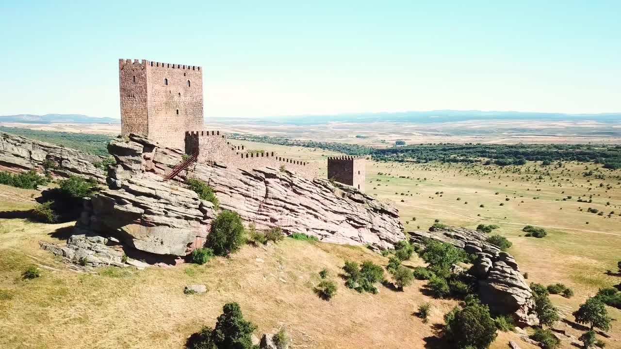 Castillo de Zafra stands atop a rugged rocky outcrop in Spain's vast countryside, showing medieval architecture and panoramic landscapes that highlight its cultural and geographical significance