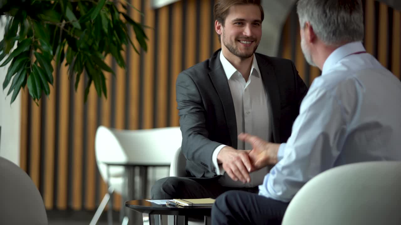 Confident caucasian mature businessman handshaking male partner at office meeting. Partnership, investment concept
