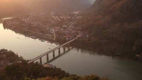 Puesta-De-Sol-Sobre-El-Río-Con-Un-Puente-Que-Lo-Cruza-En-La-Ciudad-Montañosa-De-Nong-Khiaw-En-Laos,-Sudeste-De-Asia