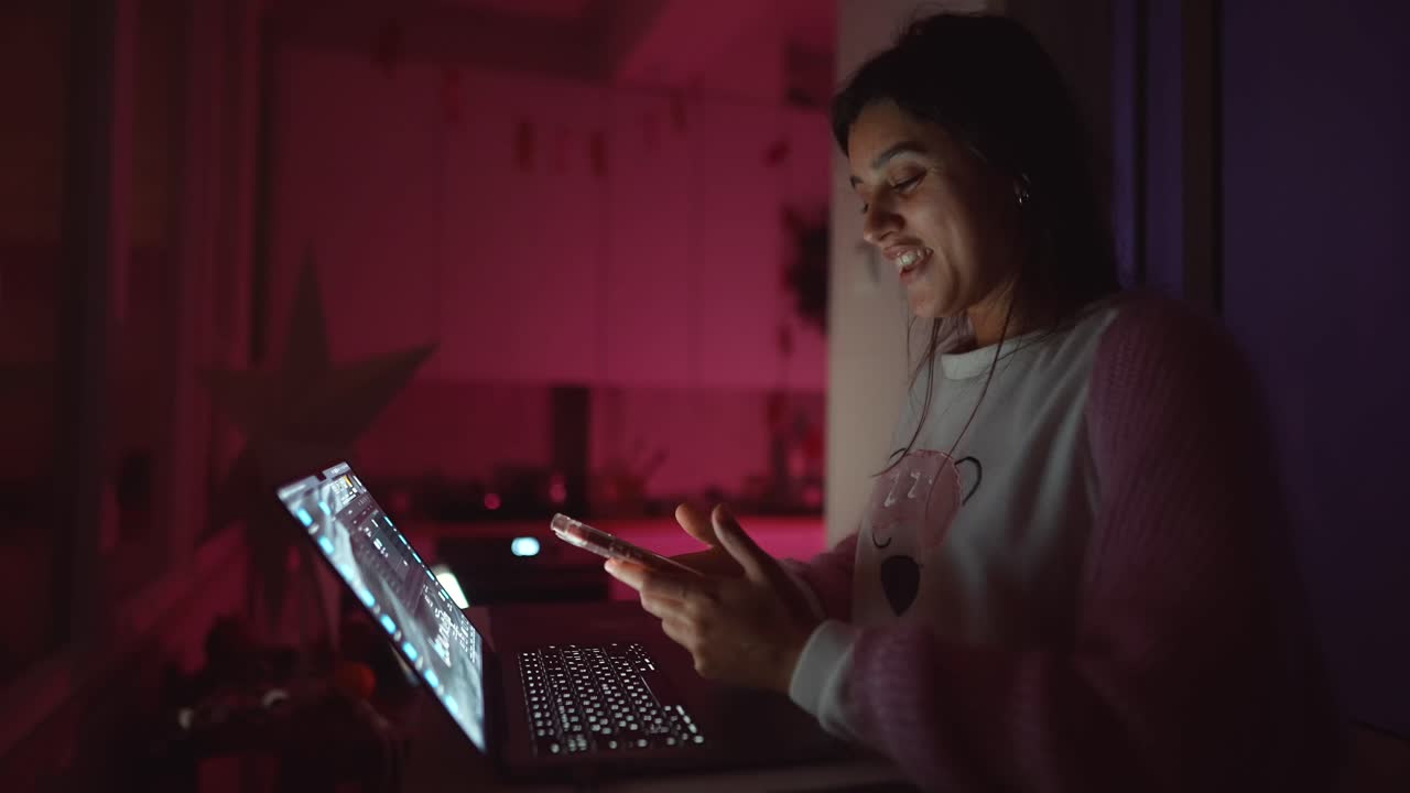 Donna che usa telefono e laptop di notte