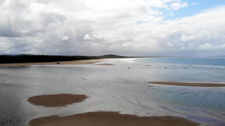 Onde sulle sabbie bianche dell'Australia, alba con il surf club sullo sfondo