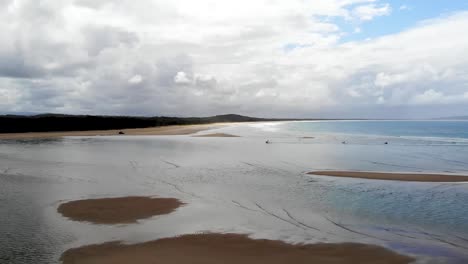 Waves-on-the-white-sands-of-Australia,-sunrise-with-the-surf-club-in-the-background