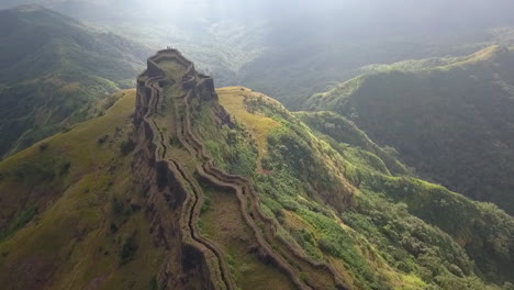 misty green aerial of zunjar machi grassy walls in torna fort, india