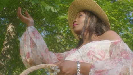 beautiful woman adjusting hair on picnic in park touching leaves low angle